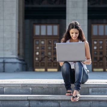 Student sitting on campus steps working on laptop.
