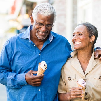 An older African-American couple walks together with ice cream cones