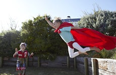Two boys play superheroes out in the backyard.