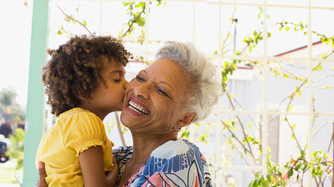 A young Black girls kisses her older Black relative