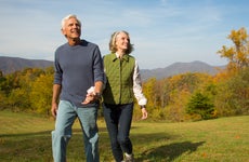 An older couple walks in a field