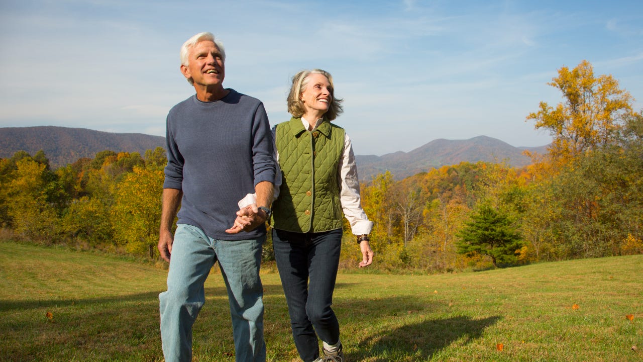 An older couple walks in a field