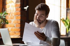 A frustrated man looks at a bill.