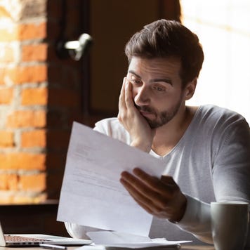 A frustrated man looks at a bill.