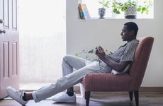 A young black man lounges about in his condo while on the phone.