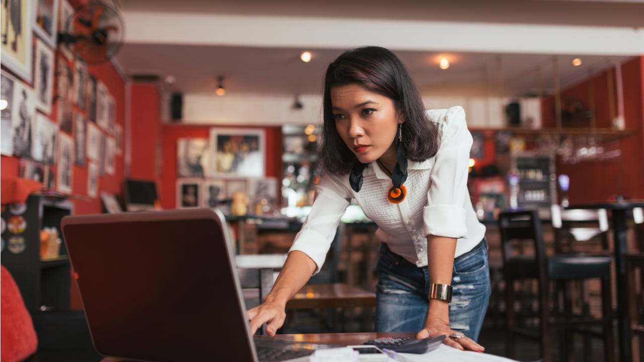 Concerned woman looks at laptop.