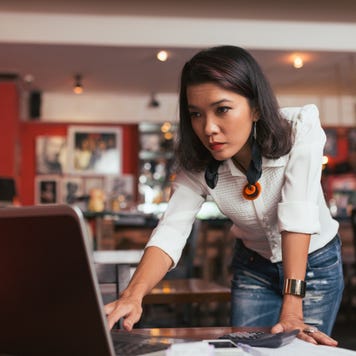 Concerned woman looks at laptop.