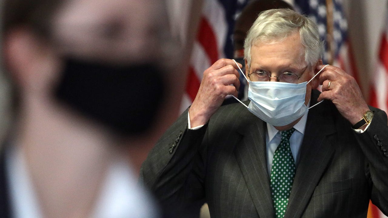 Senate Majority Leader Mitch McConnell puts on a mask