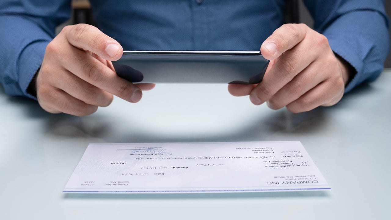 A man takes a picture of a check.