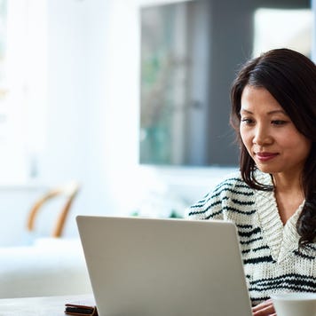 A woman sits in front of her laptop looking at her insurance and finance information