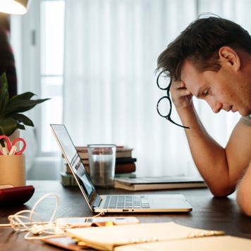 Stressed man looks at laptop