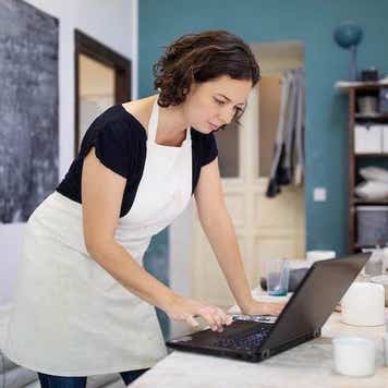 Pottery artist working on laptop at her workshop