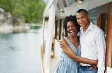 An older Black couple hangs off a boat