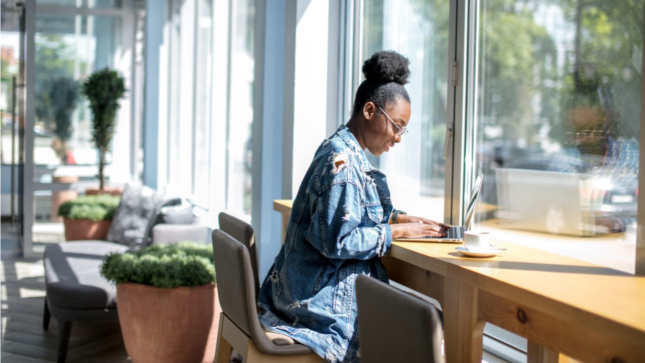 Young woman works on laptop at a cafe