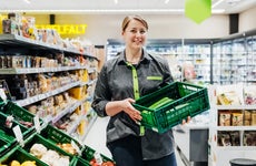 A female grocery employee holds a basket