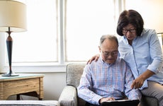 An older Asian couple sitting in their living room on a laptop, reviewing their finances.