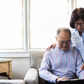 An older Asian couple sitting in their living room on a laptop, reviewing their finances.