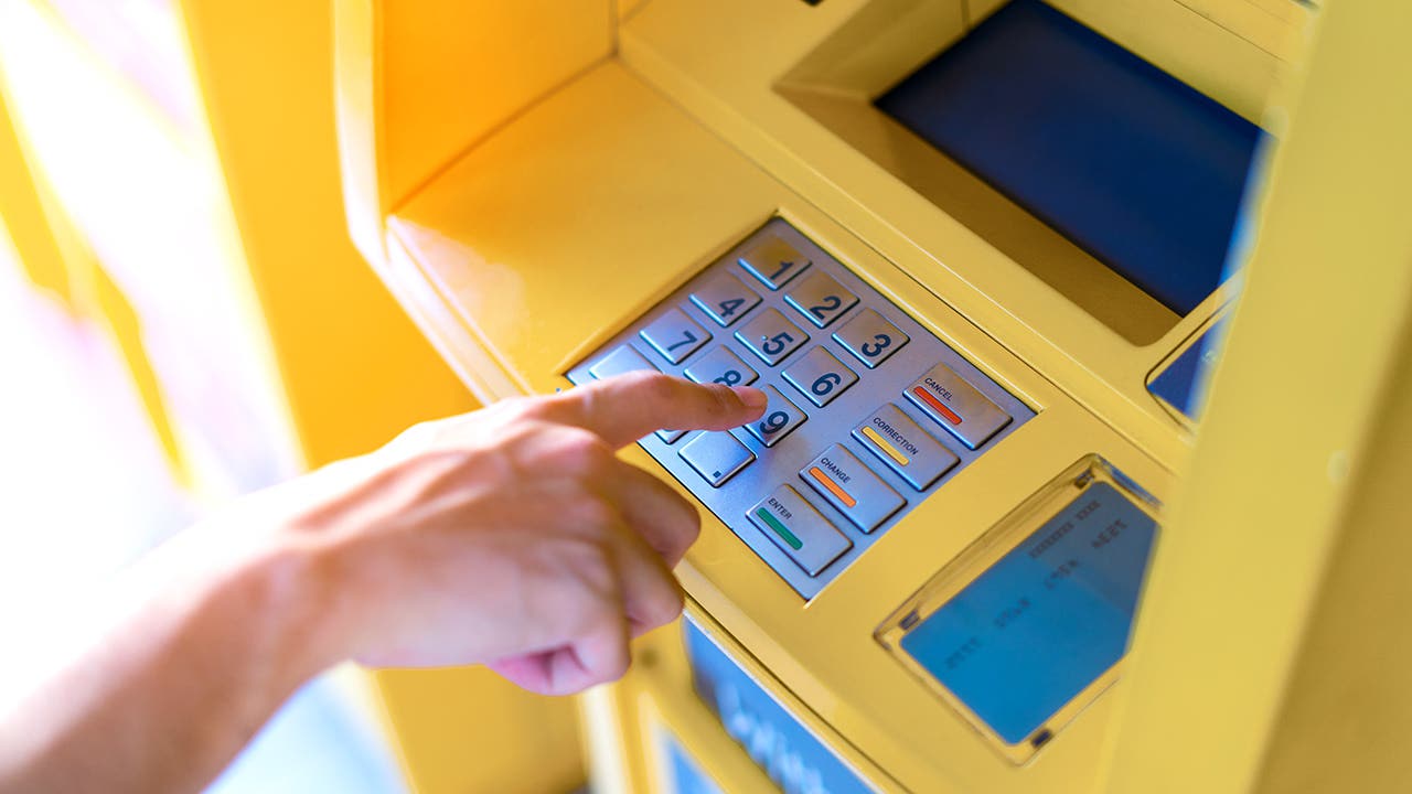 Man hand entering his PIN at an ATM