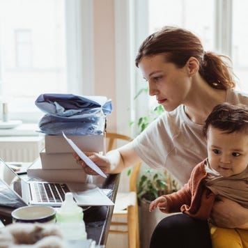 Businesswoman reading document while sitting with baby boy in living room