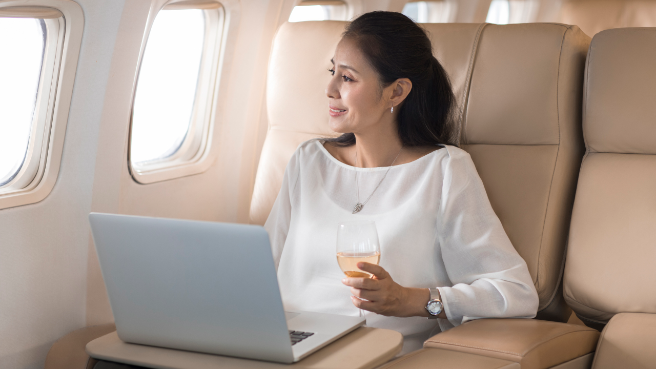 woman looking out the plane of the airplane holding a glass