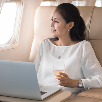 woman looking out the plane of the airplane holding a glass