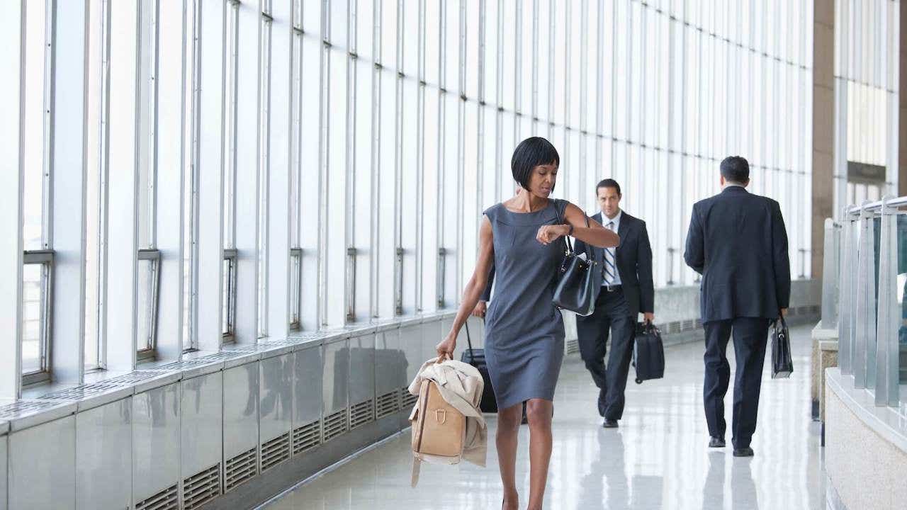 Black businesswoman checking the time on wristwatch in corridor