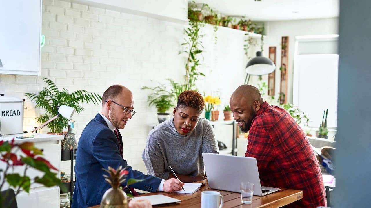 Couple listening to financial advisor at home with laptop