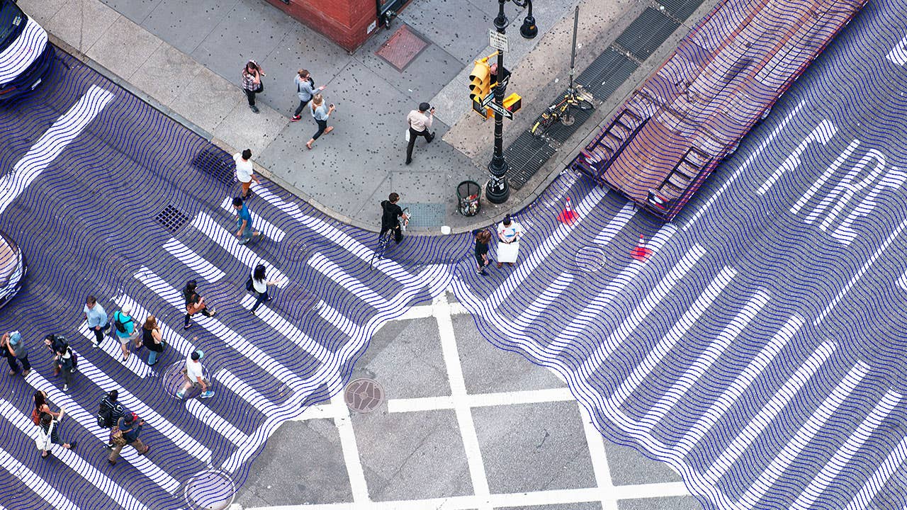 A picture from above of pedestrians crossing a busy street