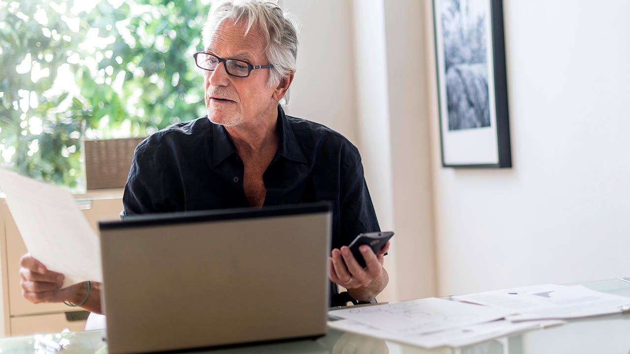Senior man sitting in home office and using laptop