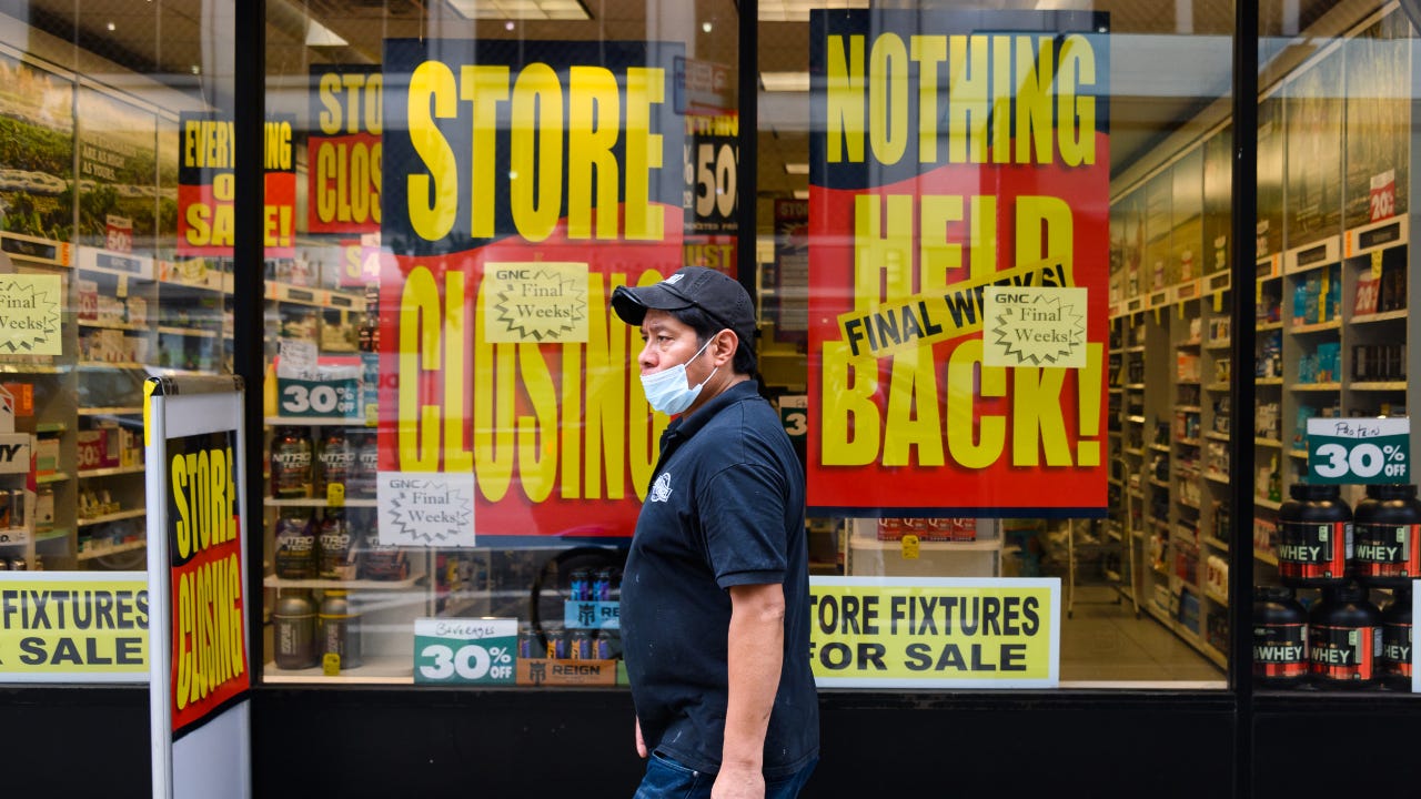 A person wears a protective face mask outside a GNC store.