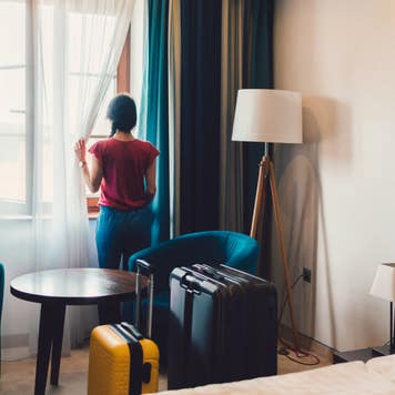 Woman looking out hotel room window