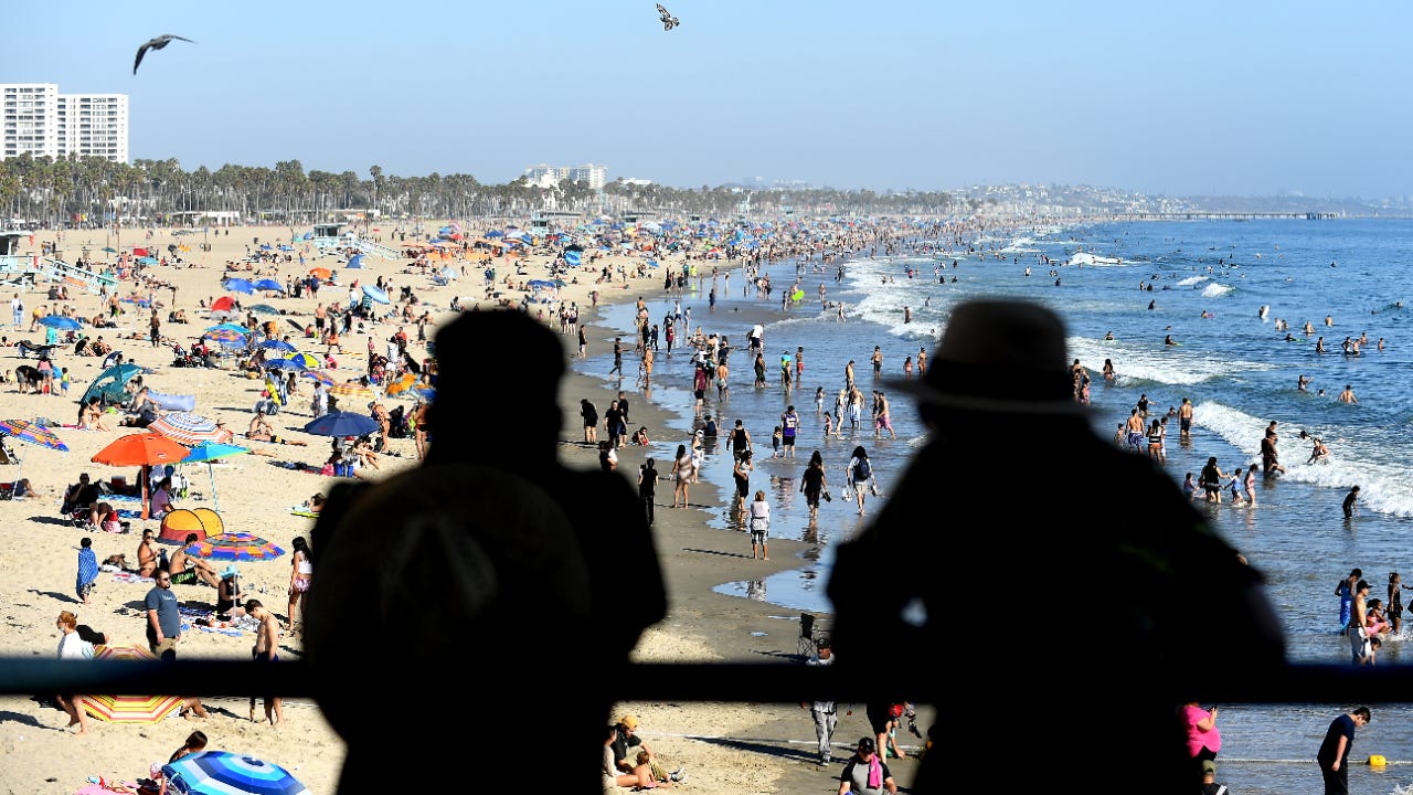 A couple looks over at a crowded beach in Santa Monica, California.