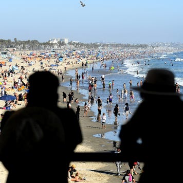 A couple looks over at a crowded beach in Santa Monica, California.