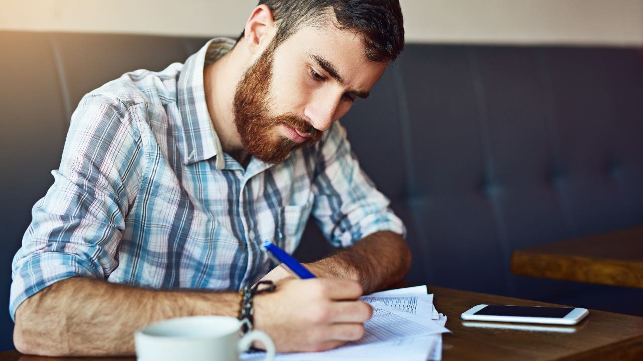 Man signs paperwork in a coffee shop