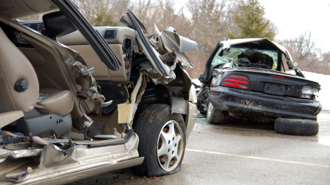 Two completely totaled cars including one with its rear window smashed in and the other missing the door on the passenger side.