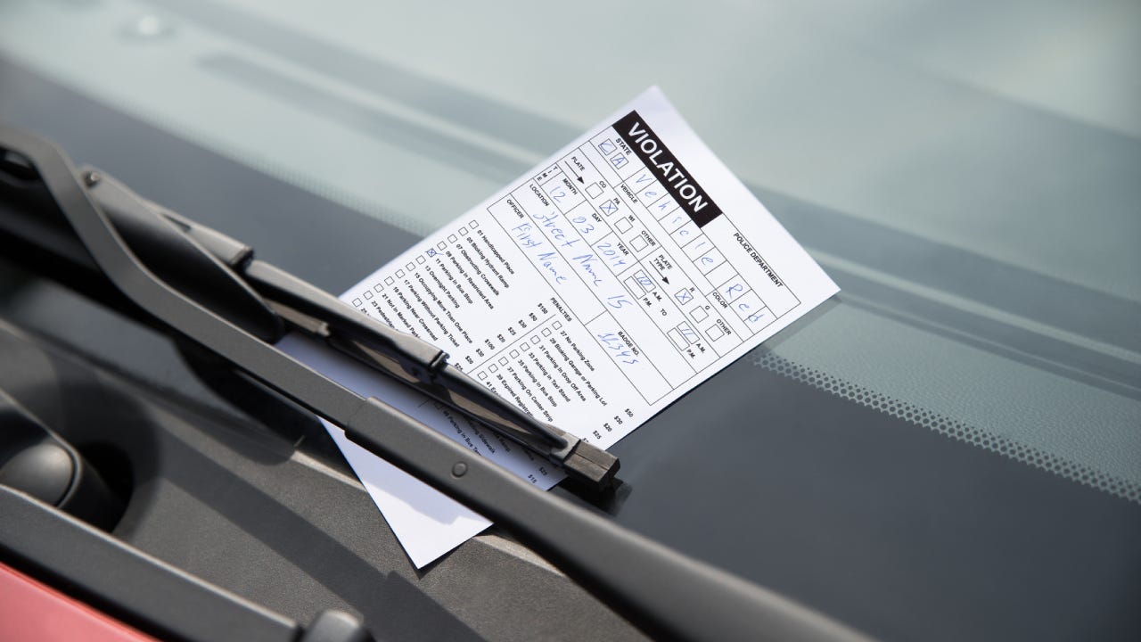 Shot of a parking ticket secured to a windshield by a wiper.