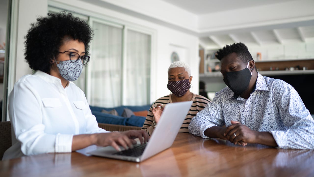 Some people wearing facemasks are on a laptop trying to figure out what to do with their life insurance policy.