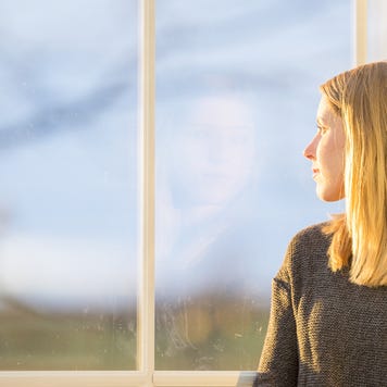 A woman sit and pensively stares out the window.