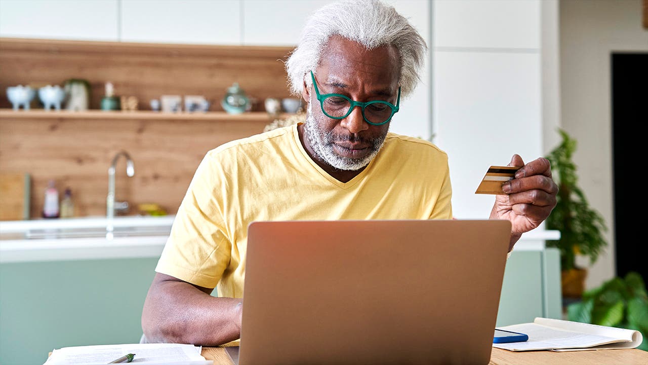 Senior man using laptop and credit card