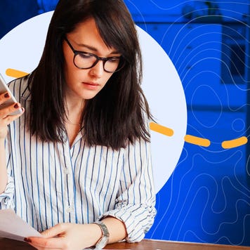 A woman holds her phone and reviews bills