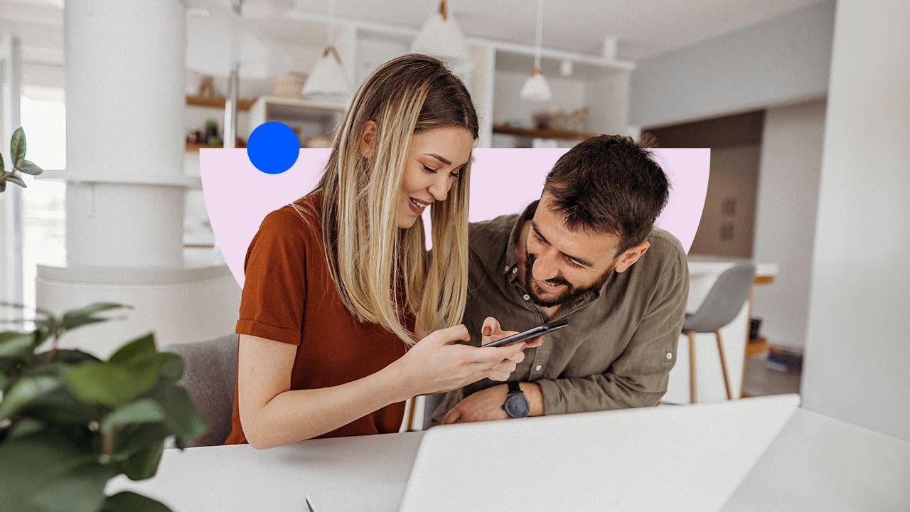 A couple happily looking at a phone screen, both smiling