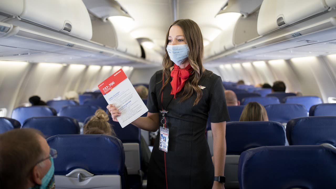Flight attendant gives instructions wearing protective mask
