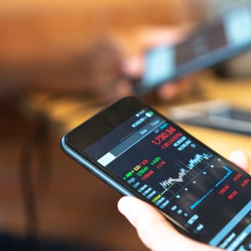 Someone holds a mobile phone with a stock chart on it