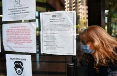 A woman wearing a facemask enters a building where the Employment Development Department has its offices in Los Angeles, California on May 4, 2020, past a posted sign mentioning the closure of the offices's public access counters due to the coronavirus pandemic. - Dismal US employment figures are expected with the release Friday May 8 of figures for April's US jobs report, with 30 million Americans filing for unemployment in the last six weeks.
