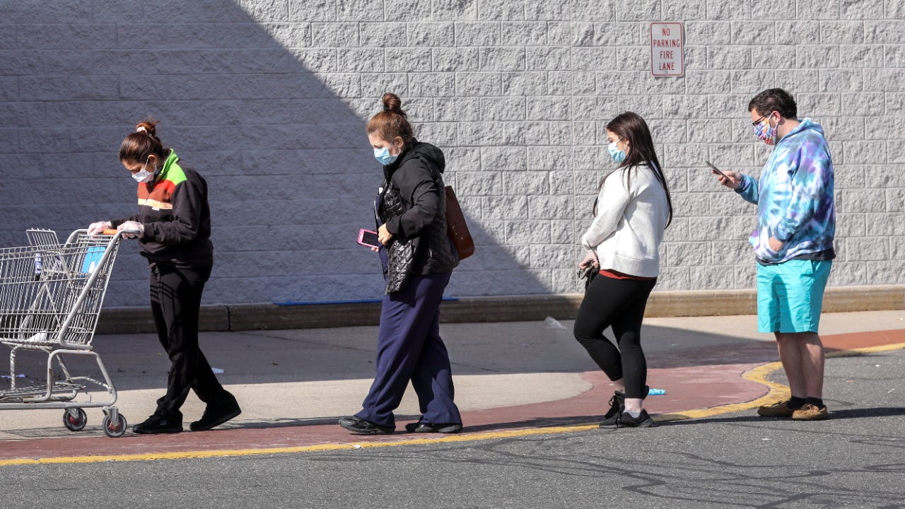 People wait outside a grocery store during the pandemic.