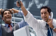 Two traders hold phones and celebrate