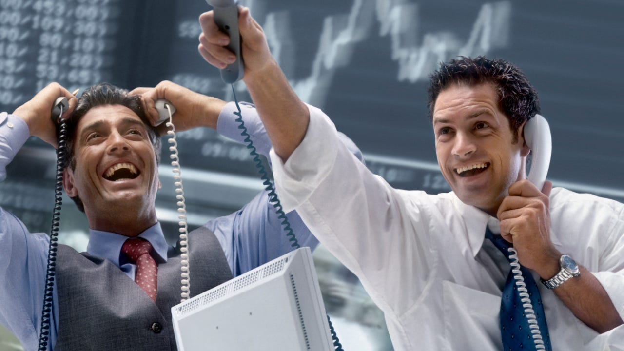 Two traders hold phones and celebrate