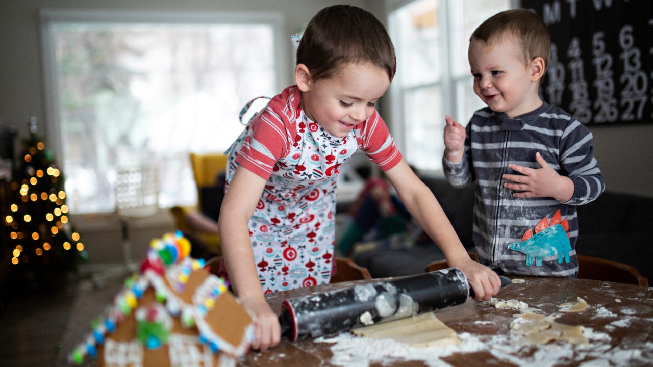 Two young brothers bake cookies together.