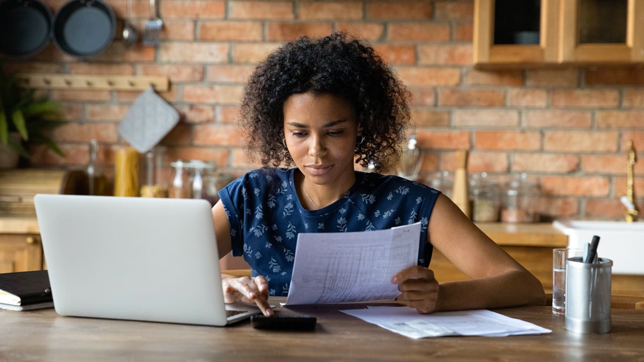 woman looking at financial papers and working on a computer