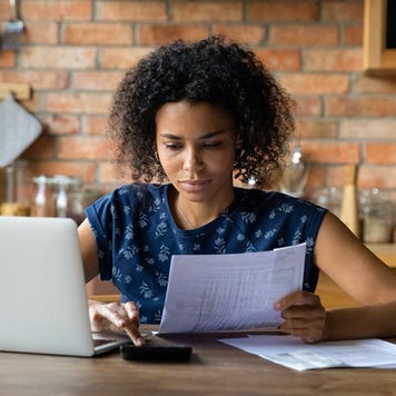 woman looking at financial papers and working on a computer